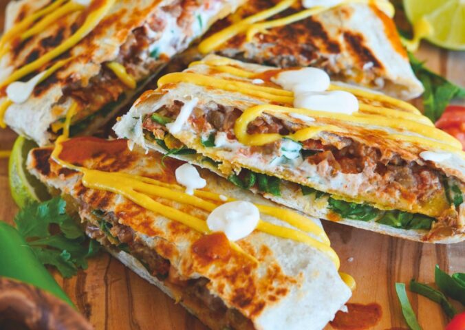 crunchy tostada wrap with corn tortilla, lentils, refired beans, vegan cheese sauce, cashew sour cream and more