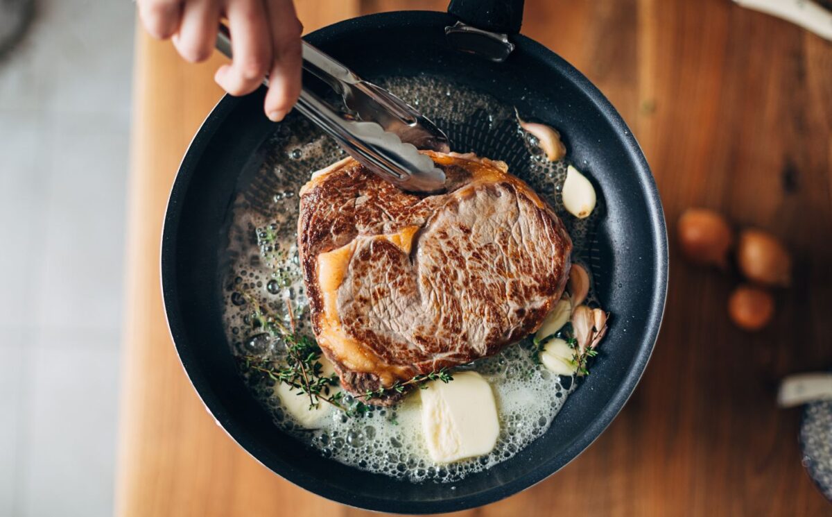 Photo shows someone cooking a steak in a cast iron pan with a lot of butter. PCRM, an American doctors’ group, has filed a lawsuit over the “industry-influenced” US dietary guidelines