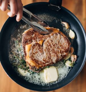 Photo shows someone cooking a steak in a cast iron pan with a lot of butter. PCRM, an American doctors’ group, has filed a lawsuit over the “industry-influenced” US dietary guidelines