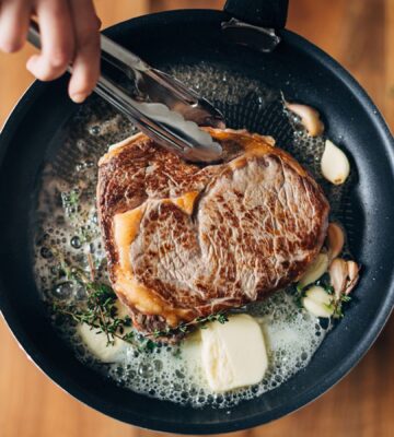 Photo shows someone cooking a steak in a cast iron pan with a lot of butter. PCRM, an American doctors’ group, has filed a lawsuit over the “industry-influenced” US dietary guidelines