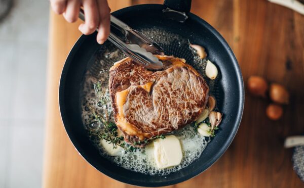 Photo shows someone cooking a steak in a cast iron pan with a lot of butter. PCRM, an American doctors’ group, has filed a lawsuit over the “industry-influenced” US dietary guidelines