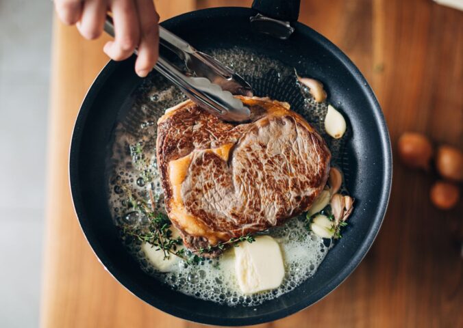 Photo shows someone cooking a steak in a cast iron pan with a lot of butter. PCRM, an American doctors’ group, has filed a lawsuit over the “industry-influenced” US dietary guidelines