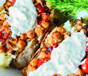 Greek-Seasoned Loaded Baked Potatoes with chickpeas, vegan sour cream, lemon, cucumber, garlic, and tomato