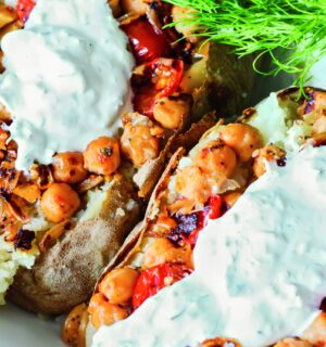 Greek-Seasoned Loaded Baked Potatoes with chickpeas, vegan sour cream, lemon, cucumber, garlic, and tomato