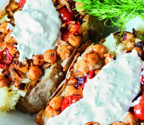 Greek-Seasoned Loaded Baked Potatoes with chickpeas, vegan sour cream, lemon, cucumber, garlic, and tomato
