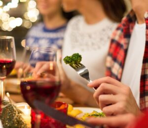 Photo shows three people eating vegetables and other meat-free options surrounded by festive lights. Nostalgia is a “major barrier” to dietary changes, including widespread adoption of plant-based diets, according to new research