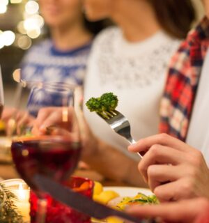 Photo shows three people eating vegetables and other meat-free options surrounded by festive lights. Nostalgia is a “major barrier” to dietary changes, including widespread adoption of plant-based diets, according to new research
