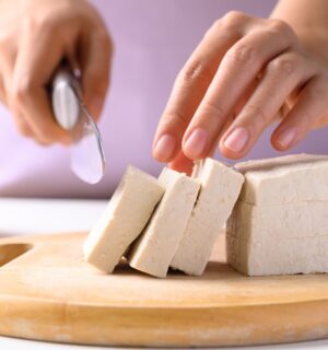 Photo shows someone cutting up a block of tofu. According to a scientist’s new scoring system, tofu is the single best protein for nutrition, sustainability, and affordability