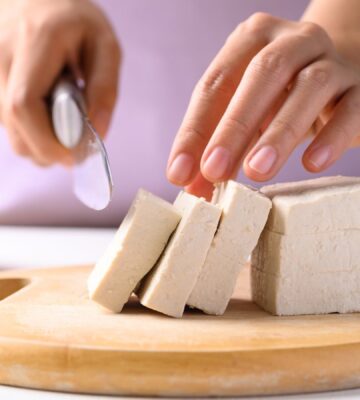 Photo shows someone cutting up a block of tofu. According to a scientist’s new scoring system, tofu is the single best protein for nutrition, sustainability, and affordability