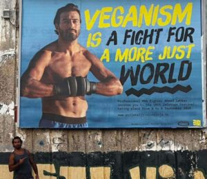Photo shows vegan MMA fighter Ahmed Labban posing next to a billboard that features him and advertises ZeGeVege Festival, an upcoming vegetarian event
