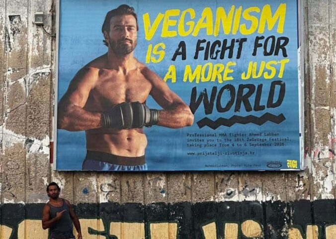 Photo shows vegan MMA fighter Ahmed Labban posing next to a billboard that features him and advertises ZeGeVege Festival, an upcoming vegetarian event
