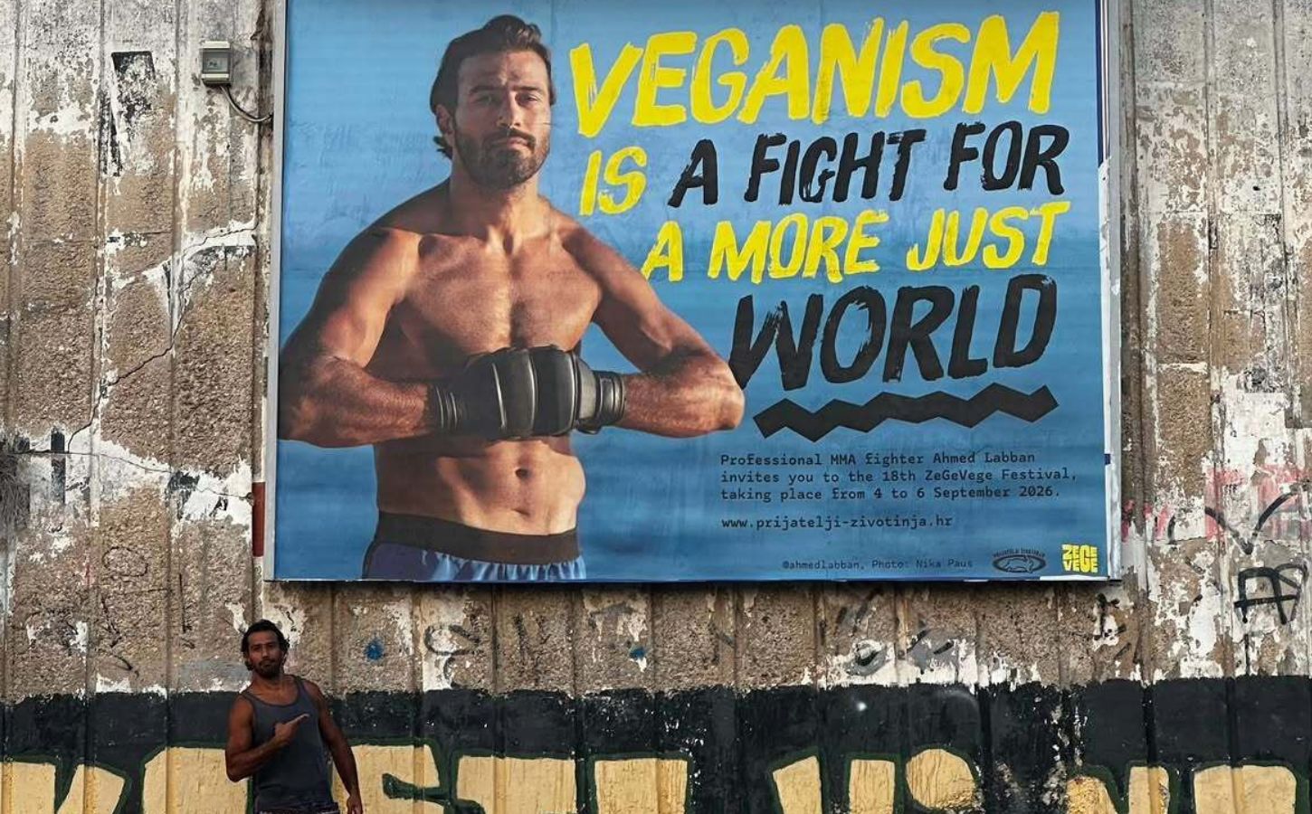 Photo shows vegan MMA fighter Ahmed Labban posing next to a billboard that features him and advertises ZeGeVege Festival, an upcoming vegetarian event