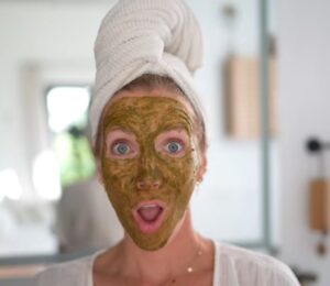 Image of Stanczyk with her hair wrapped in a white towel and her face covered in her matcha glow mask to illustrate article about DIY Plant-based spa treatments.