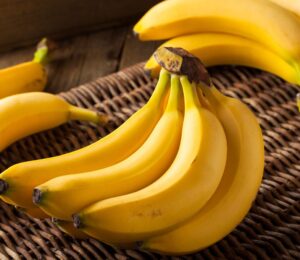 A bunch of ripe yellow bananas resting on a woven straw basket, to illustrate article about frozen and thawed bananas