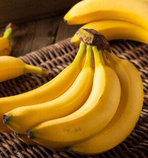 A bunch of ripe yellow bananas resting on a woven straw basket, to illustrate article about frozen and thawed bananas
