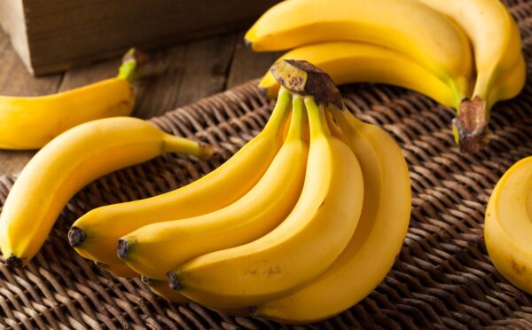 A bunch of ripe yellow bananas resting on a woven straw basket, to illustrate article about frozen and thawed bananas