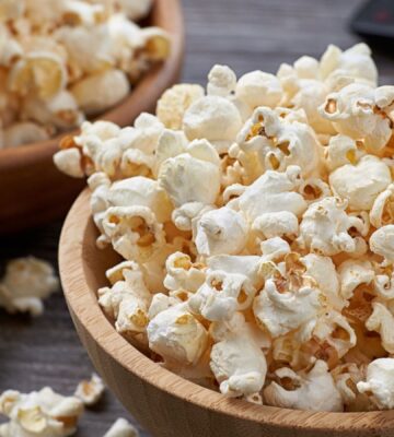 Two wooden bowls overflowing with freshly popped popcorn, highlighting the benefits of air-popped popcorn as a whole-grain snack