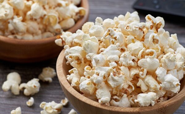Two wooden bowls overflowing with freshly popped popcorn, highlighting the benefits of air-popped popcorn as a whole-grain snack