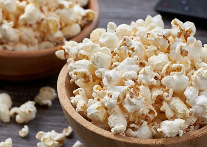Two wooden bowls overflowing with freshly popped popcorn, highlighting the benefits of air-popped popcorn as a whole-grain snack