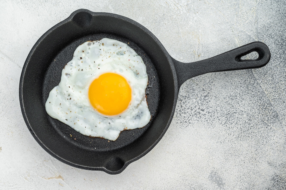 Fried egg in a black pan to illustrate article comparing tofu vs eggs