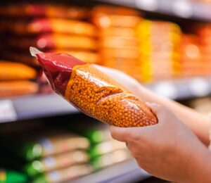 Photo shows someone holding a pack of red lentils in a supermarket aisle. Britons are buying less fake meat, but more beans and tofu, according to a new analysis of retail data