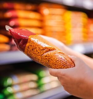 Photo shows someone holding a pack of red lentils in a supermarket aisle. Britons are buying less fake meat, but more beans and tofu, according to a new analysis of retail data