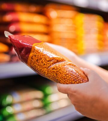 Photo shows someone holding a pack of red lentils in a supermarket aisle. Britons are buying less fake meat, but more beans and tofu, according to a new analysis of retail data