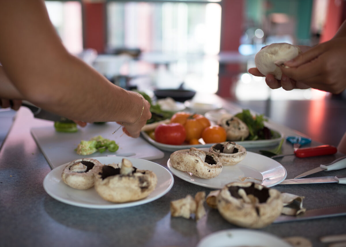 Photo shows people's hands as they prepare a meal using plant-based ingredients like mushrooms and vegetables. A team of experts has designed a full week of balanced plant-based meals for Dutch hospitals