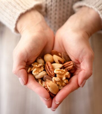 Photo shows someone using two hands to cup a selection of nuts. A new study has found that eating just one handful of nuts per day can reduce the risk of developing high blood pressure by 20 percent