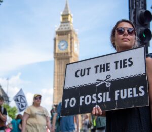 Photo shows a young woman protesting in London and holding a sign that reads: "Cut the ties to fossil fuels." The London Science Museum has cut ties with BP after decades of campaigning from activists, scientists, and schools