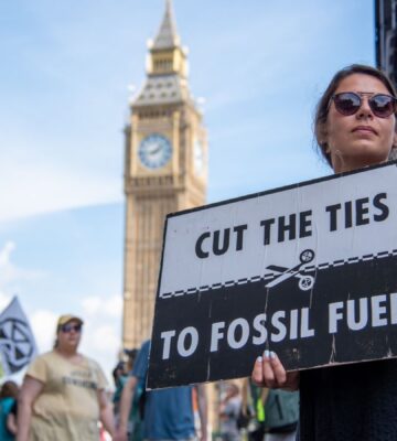 Photo shows a young woman protesting in London and holding a sign that reads: "Cut the ties to fossil fuels." The London Science Museum has cut ties with BP after decades of campaigning from activists, scientists, and schools
