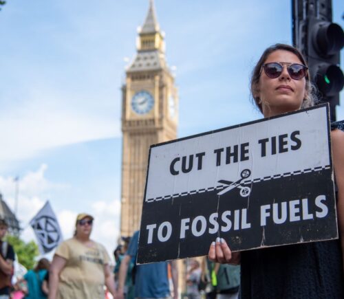 Photo shows a young woman protesting in London and holding a sign that reads: "Cut the ties to fossil fuels." The London Science Museum has cut ties with BP after decades of campaigning from activists, scientists, and schools