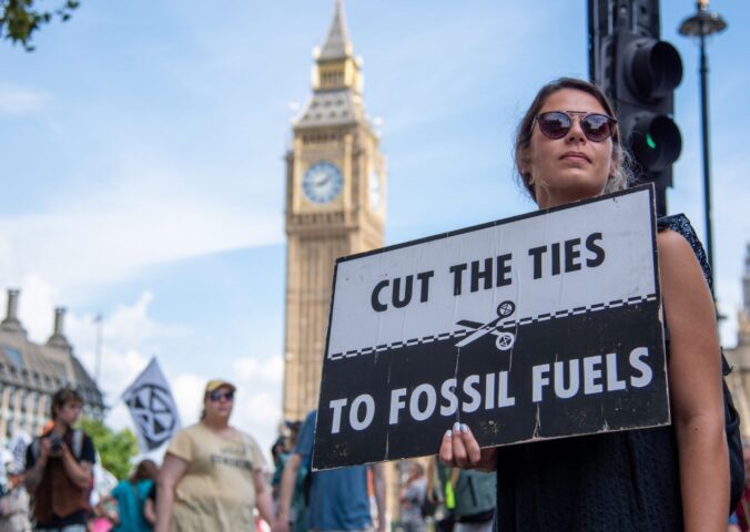 Photo shows a young woman protesting in London and holding a sign that reads: "Cut the ties to fossil fuels." The London Science Museum has cut ties with BP after decades of campaigning from activists, scientists, and schools