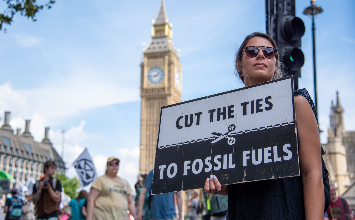 Photo shows a young woman protesting in London and holding a sign that reads: "Cut the ties to fossil fuels." The London Science Museum has cut ties with BP after decades of campaigning from activists, scientists, and schools