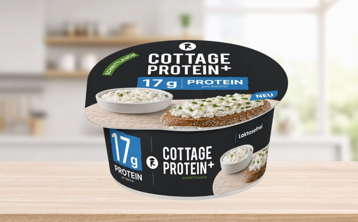 Photo shows the new vegan cottage cheese product, COTTAGE PROTEIN+, from Austrian food tech startup Revo Foods, against a stock kitchen background. The packaging is black, blue, and white. Revo Foods just launched a high-protein vegan cottage cheese made with fermented, upcycled apricot kernels