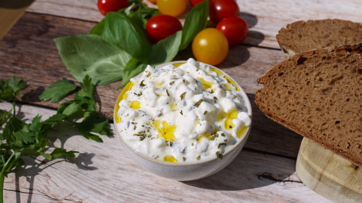 Photo shows a bowl of the new vegan cottage cheese from Revo Foods, COTTAGE PROTEIN+, on a table with bread and salad