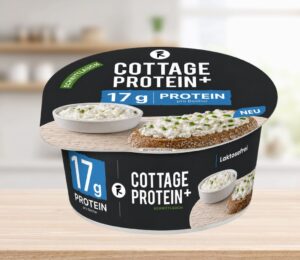 Photo shows the new vegan cottage cheese product, COTTAGE PROTEIN+, from Austrian food tech startup Revo Foods, against a stock kitchen background. The packaging is black, blue, and white. Revo Foods just launched a high-protein vegan cottage cheese made with fermented, upcycled apricot kernels