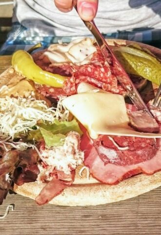 Photo shows someone eating a large plate of various different meats and cheeses on a picnic table in Switzerland. A new study has found that Switzerland’s meat and dairy consumption is up to 850 percent higher than recommended by the EAT-Lancet Planetary Health Diet. The study also found that many Swiss people significantly “underconsume” key plant-based foods, such as legumes