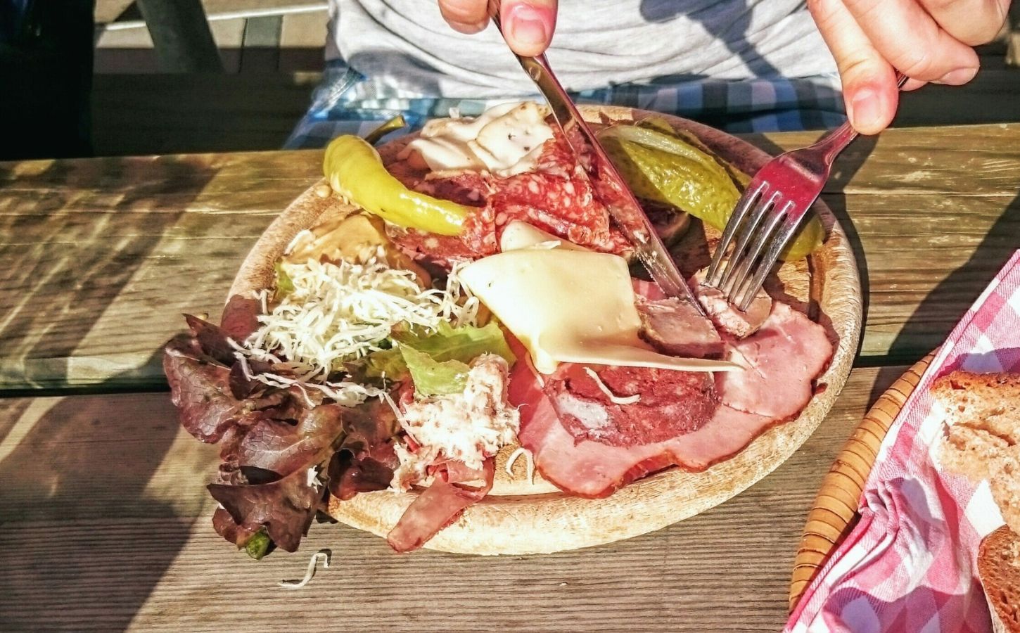 Photo shows someone eating a large plate of various different meats and cheeses on a picnic table in Switzerland. A new study has found that Switzerland’s meat and dairy consumption is up to 850 percent higher than recommended by the EAT-Lancet Planetary Health Diet. The study also found that many Swiss people significantly “underconsume” key plant-based foods, such as legumes