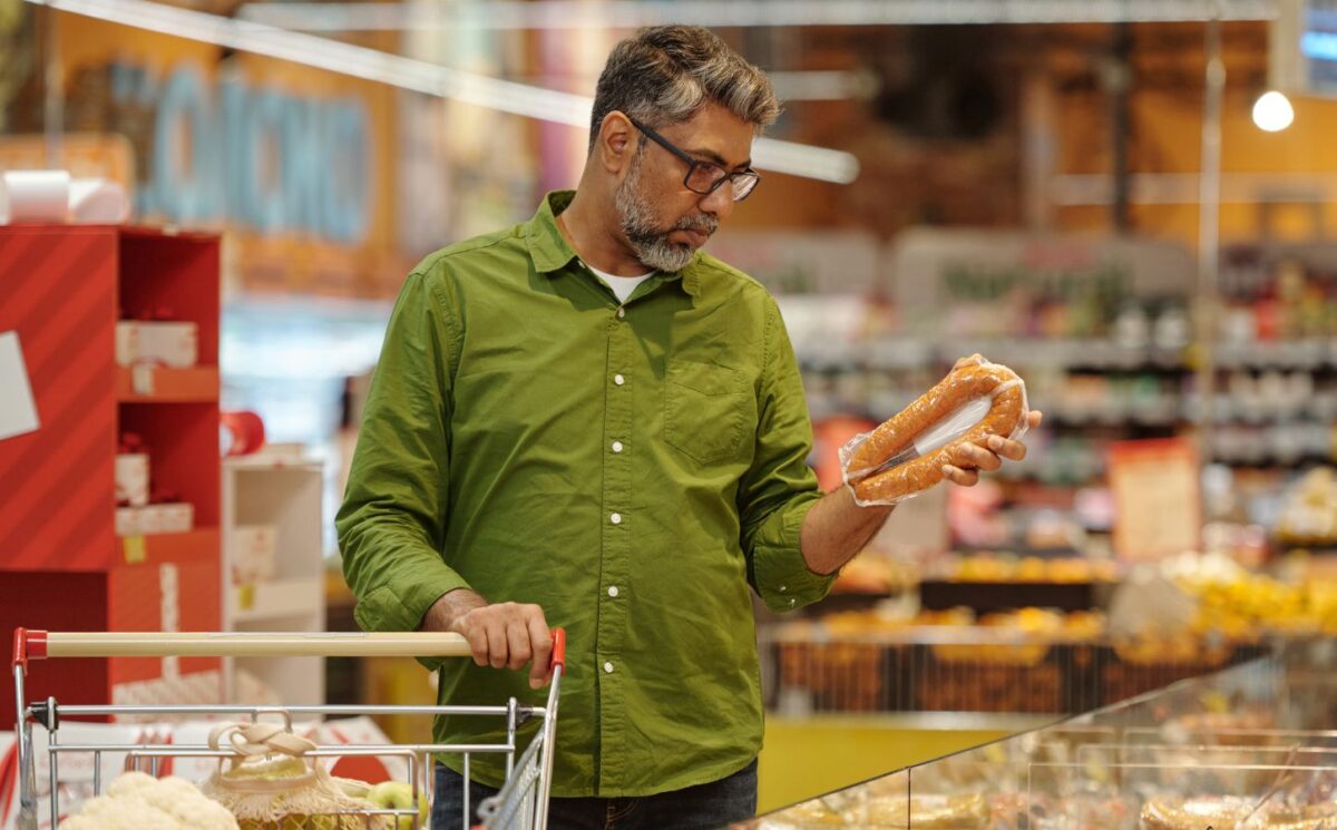 Photo shows a man shopping in a supermarket and holding up a meat-based sausage product. A new survey has found that almost no UK shoppers actually mistake plant-based alternatives for animal-derived meat