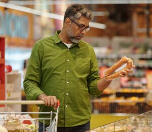 Photo shows a man shopping in a supermarket and holding up a meat-based sausage product. A new survey has found that almost no UK shoppers actually mistake plant-based alternatives for animal-derived meat