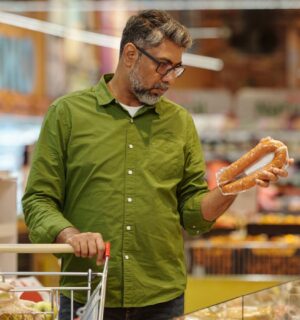 Photo shows a man shopping in a supermarket and holding up a meat-based sausage product. A new survey has found that almost no UK shoppers actually mistake plant-based alternatives for animal-derived meat