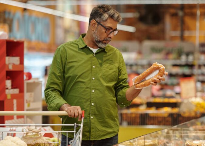 Photo shows a man shopping in a supermarket and holding up a meat-based sausage product. A new survey has found that almost no UK shoppers actually mistake plant-based alternatives for animal-derived meat