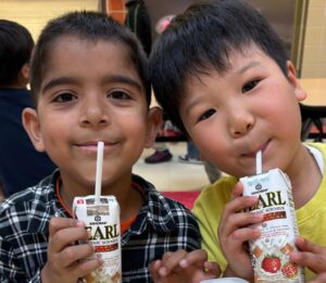 Photo shows two kids drinking soy milk out of cartons during school lunch. New data shows that a soy milk pilot program in New York City (NYC) schools found strong student demand and reduced greenhouse gas emissions (GHGs) by 17.4 percent
