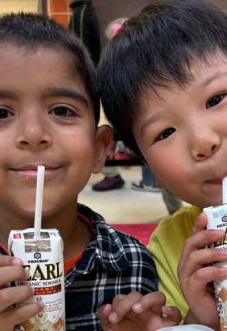 Photo shows two kids drinking soy milk out of cartons during school lunch. New data shows that a soy milk pilot program in New York City (NYC) schools found strong student demand and reduced greenhouse gas emissions (GHGs) by 17.4 percent
