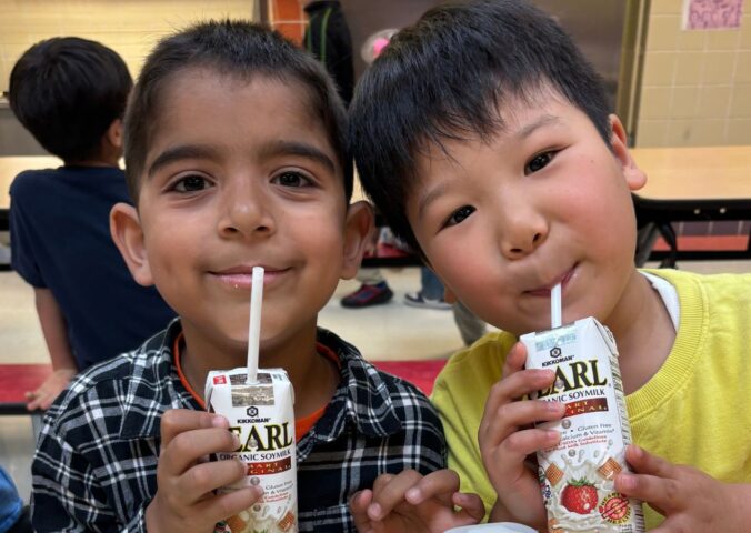 Photo shows two kids drinking soy milk out of cartons during school lunch. New data shows that a soy milk pilot program in New York City (NYC) schools found strong student demand and reduced greenhouse gas emissions (GHGs) by 17.4 percent