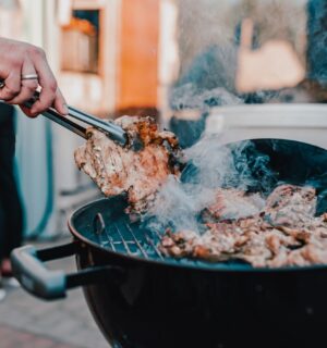 Photo shows a man's hand as he BBQs red meat. Scientists analyzed the supposed benefits of carnivore diets and found the evidence base to be “thin.”