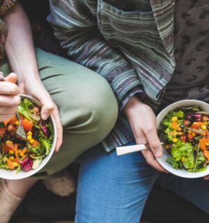 Photo shows two people holding bowls of colorful vegetables and other plant foods. Most people in the UK would be willing to cut their meat and dairy consumption in order to improve food security, according to a new survey