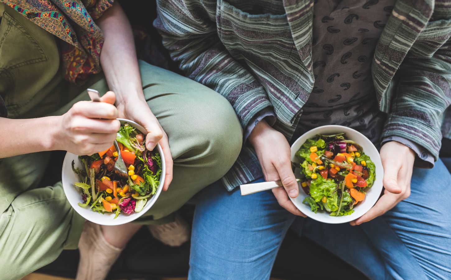 Photo shows two people holding bowls of colorful vegetables and other plant foods. Most people in the UK would be willing to cut their meat and dairy consumption in order to improve food security, according to a new survey